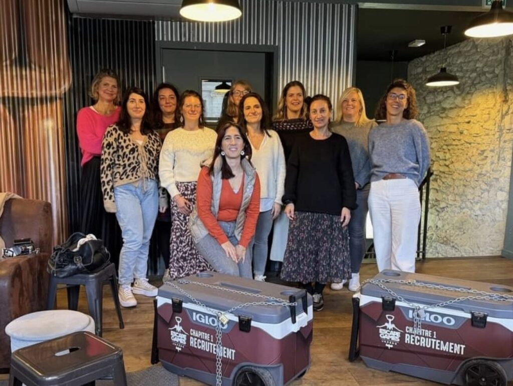 Groupe de femmes qui sourient dans une salle chaleureuse qui s'apprêtent à faire l'Escape Game l'Apéro